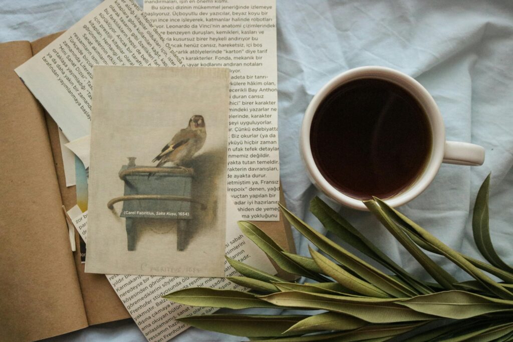 Flat lay of coffee cup, art print, and papers, invoking a cozy atmosphere.
